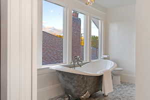 Cast iron claw foot tub, brass faucet, and designer lighting