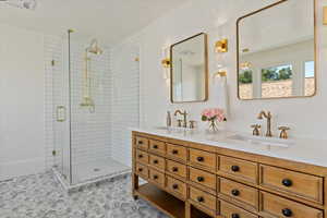 Glass box shower, floral tile, solid hardwood vanity, brass faucets, and designer lighting