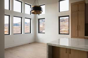 Unfurnished dining area featuring a mountain view, light wood-type flooring, and a notable chandelier