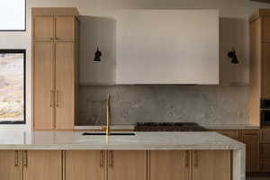 Kitchen with light brown cabinetry, tasteful backsplash, and sink