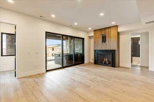 Unfurnished living room featuring a large fireplace and light hardwood / wood-style flooring