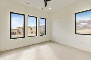 Empty room with ceiling fan, a mountain view, and carpet