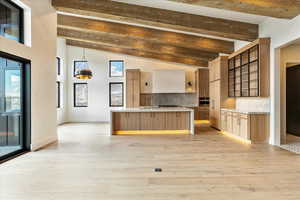 Kitchen with hanging light fixtures, oven, backsplash, and lofted ceiling with beams