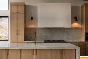 Kitchen with light brown cabinetry, sink, and decorative backsplash