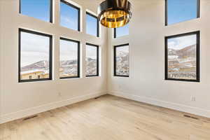 Empty room featuring a mountain view, light hardwood / wood-style floors, and a towering ceiling