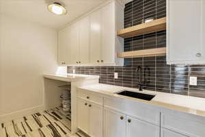 Kitchen featuring white cabinets, sink, and backsplash