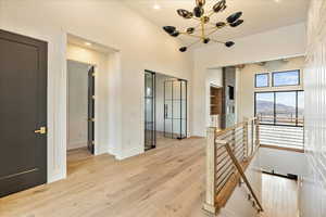 Hallway featuring light wood-type flooring and a notable chandelier