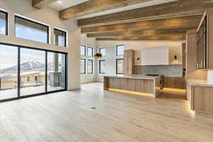 Kitchen featuring high end stove, beamed ceiling, a mountain view, and light wood-type flooring