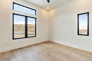 Empty room with ceiling fan and light hardwood / wood-style flooring