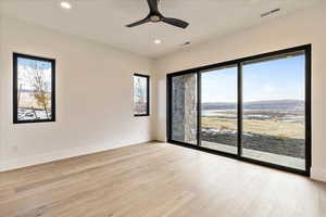 Unfurnished room featuring light wood-type flooring, a mountain view, and ceiling fan