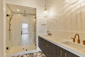 Bathroom with walk in shower, vanity, and an inviting chandelier