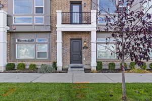 View of exterior entry featuring a lawn and a balcony