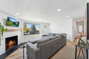 Living room with light wood-type flooring, a textured ceiling, and a tile fireplace