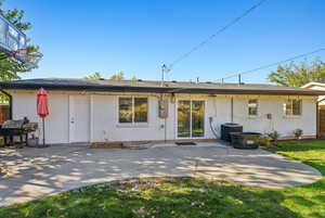 Back of property with central AC unit, a patio, and a yard