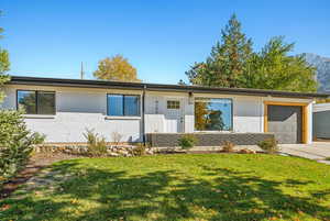 Single story home with a garage and a front lawn