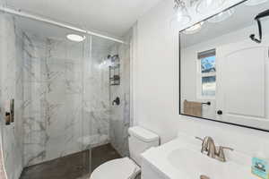 Bathroom with walk in shower, vanity, toilet, and a textured ceiling