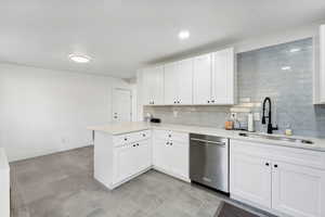 Kitchen featuring white cabinets, kitchen peninsula, sink, tasteful backsplash, and stainless steel dishwasher