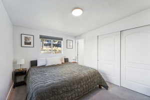 Carpeted bedroom featuring a textured ceiling and a closet