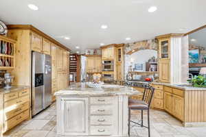 Kitchen featuring kitchen peninsula, stainless steel fridge, light stone counters, a breakfast bar, and a kitchen island