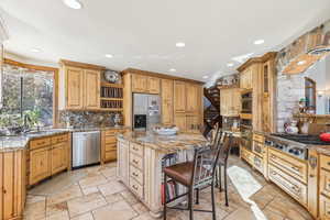 Kitchen with light stone counters, a kitchen bar, a kitchen island, and appliances with stainless steel finishes