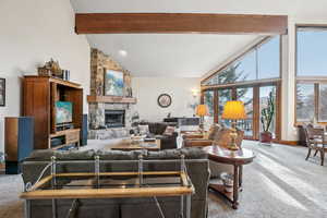 Carpeted living room with a fireplace, high vaulted ceiling, and beamed ceiling