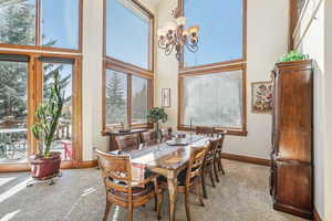 Dining room with a towering ceiling, light carpet, and a notable chandelier