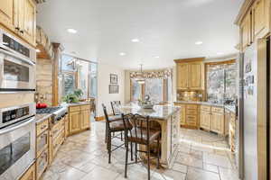 Kitchen with backsplash, a kitchen breakfast bar, hanging light fixtures, appliances with stainless steel finishes, and a kitchen island