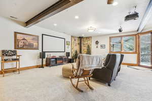 Carpeted home theater room featuring beamed ceiling