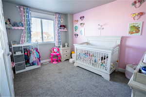 Bedroom featuring carpet and a crib