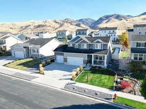 View of front of home with a garage, a front yard, a mountain view, and covered porch