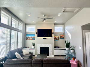 Living room featuring a tiled fireplace, a healthy amount of sunlight, and a textured ceiling