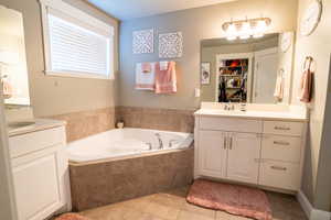 Bathroom with vanity, tiled bath, and tile patterned floors