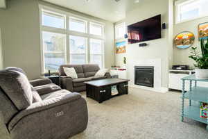 Carpeted living room with a fireplace and a towering ceiling