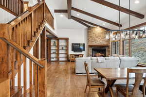 Dining space with a fireplace, wood-type flooring, high vaulted ceiling, and beam ceiling