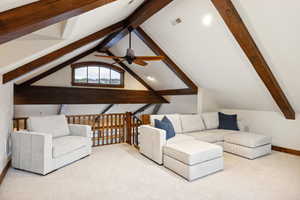 Living room featuring ceiling fan, vaulted ceiling with beams, and light colored carpet