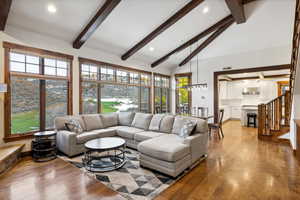 Living room with beam ceiling, light wood-type flooring, and high vaulted ceiling