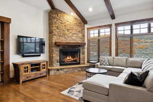 Living room featuring high vaulted ceiling, beamed ceiling, hardwood / wood-style flooring, and a fireplace