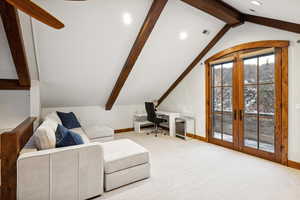 Carpeted living room featuring french doors and lofted ceiling with beams