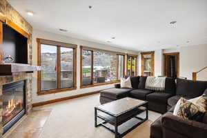 Carpeted living room with a stone fireplace and a wealth of natural light