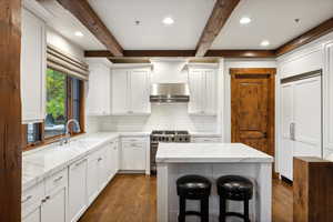 Kitchen with beam ceiling, sink, backsplash, and high end stove