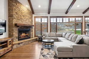 Living room featuring a fireplace, wood-type flooring, and beamed ceiling