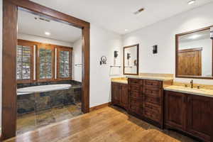 Bathroom with vanity, tiled bath, and hardwood / wood-style flooring