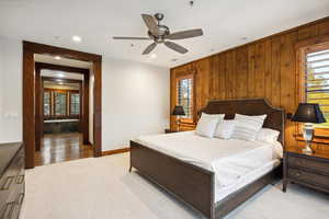 Bedroom with wooden walls, ceiling fan, and light hardwood / wood-style flooring