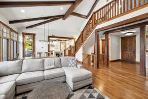 Living room with high vaulted ceiling, beamed ceiling, and hardwood / wood-style flooring