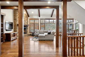 Living room featuring a fireplace, hardwood / wood-style floors, vaulted ceiling with beams, and plenty of natural light