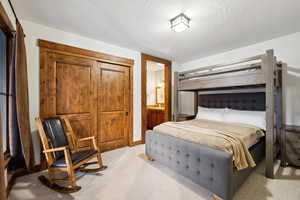 Bedroom with a textured ceiling, ensuite bath, and light carpet