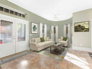 Living room with a ceiling fan, french doors, and baseboards