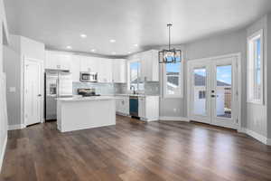 Kitchen featuring appliances with stainless steel finishes, a center island, pendant lighting, and white cabinets