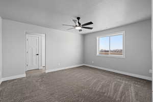 Owner's suite featuring ceiling fan and a textured ceiling