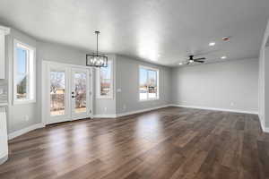 Interior space featuring french doors, dark hardwood / wood-style floors, ceiling fan with notable chandelier, and a textured ceiling